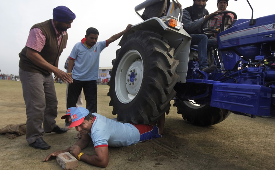In a show of strength, two men lie on the grounds and allow a tractor carrying three adults to pass over them. AP In a show of strength, two men lie on the grounds and allow a tractor carrying three adults to pass over them. AP
