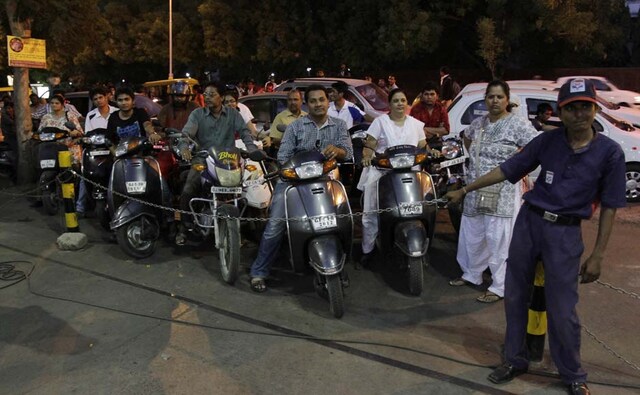 This is not a rock concert: A petrol pump guard holds a chain to control the rush at the station. AP This is not a rock concert: A petrol pump guard holds a chain to control the rush at the station. AP