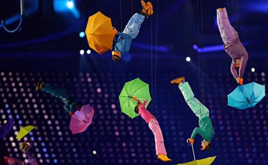 Performers with umbrellasare suspended in the air. AP Performers with umbrellasare suspended in the air. AP