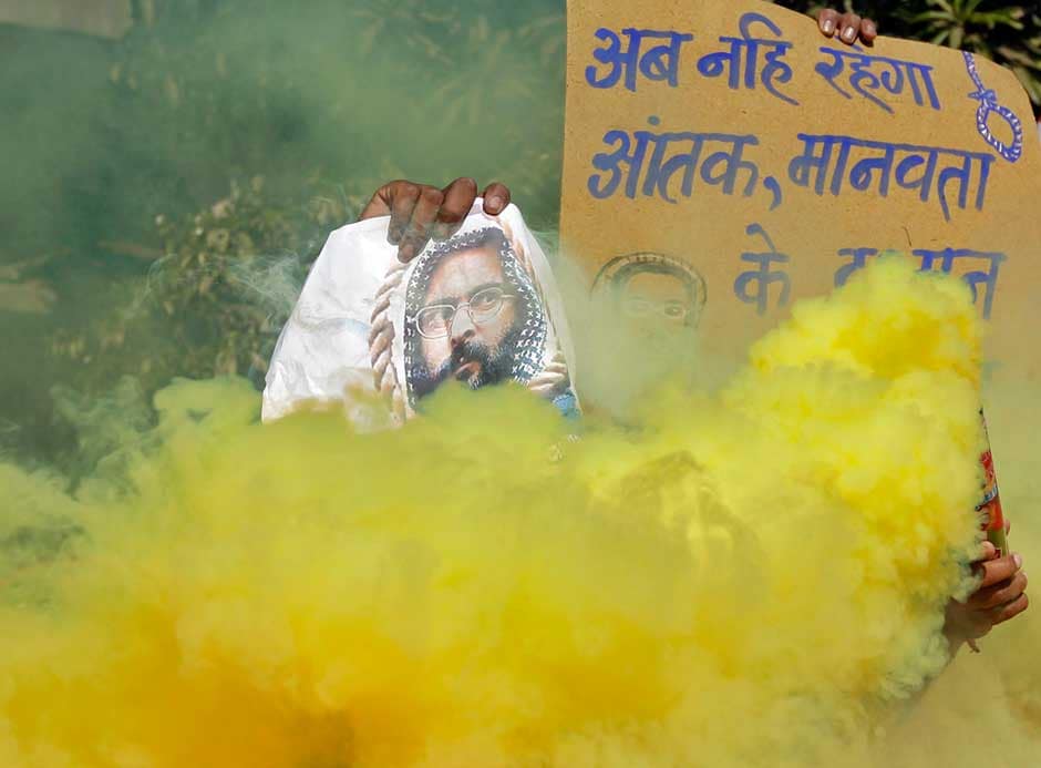 A demonstrator holds a poster of Mohammad Afzal Guru as another releases coloured smoke during celebrations in the western Indian city of Ahmedabad today.Reuters A demonstrator holds a poster of Mohammad Afzal Guru as another releases coloured smoke during celebrations in the western Indian city of Ahmedabad today.Reuters