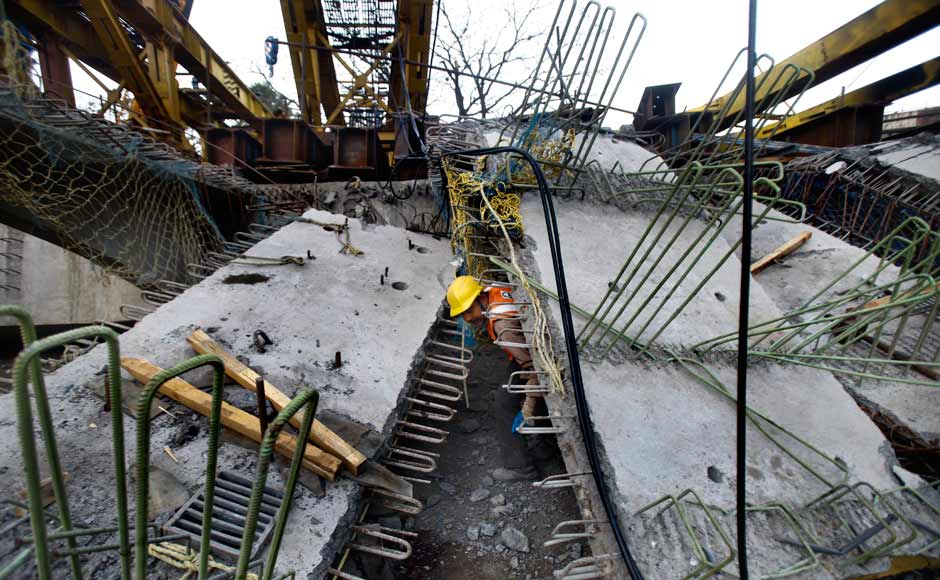 A worker examines the rubble from the collapse of an under-construction flyover in suburban Andheri in Mumbai late last night. AP A worker examines the rubble from the collapse of an under-construction flyover in suburban Andheri in Mumbai late last night. AP