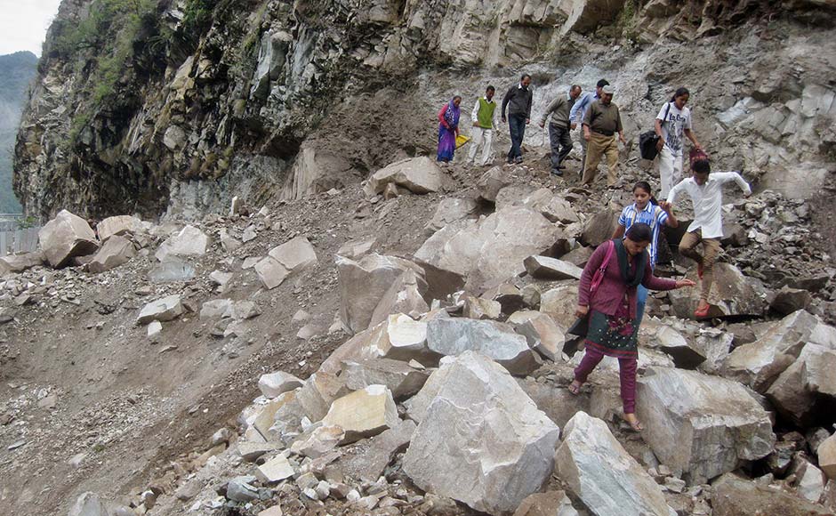 People walk on a mountain near a highway damaged by a landslide in Chamoli district, in Uttarakhand. AP People walk on a mountain near a highway damaged by a landslide in Chamoli district, in Uttarakhand. AP