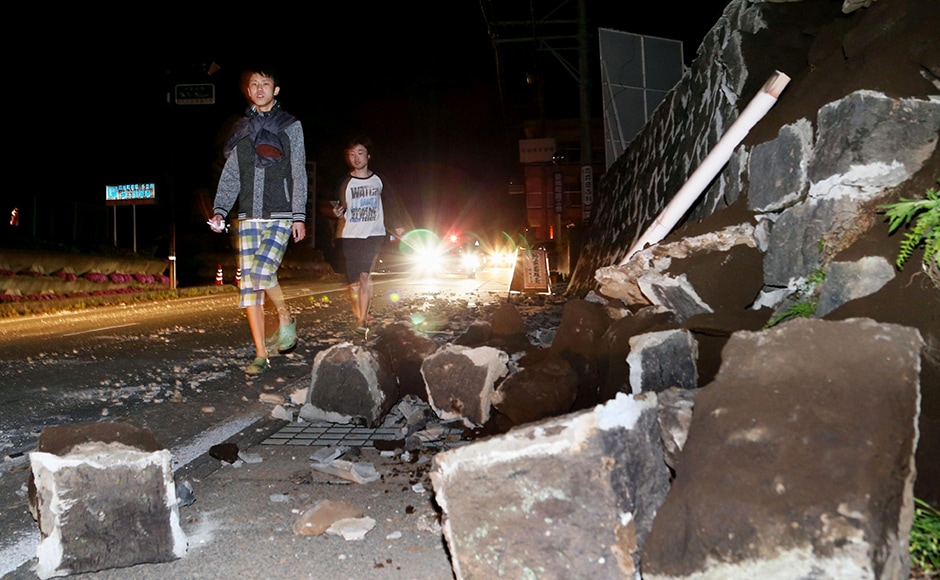 People walk past fallen walls after an earthquake of 6.4 magnitude hit the town of Mashiki, in Kumamoto, southern Japan on Thursday. Police said people were trapped underneath the rubble. AP People walk past fallen walls after an earthquake of 6.4 magnitude hit the town of Mashiki, in Kumamoto, southern Japan on Thursday. Police said people were trapped underneath the rubble. AP