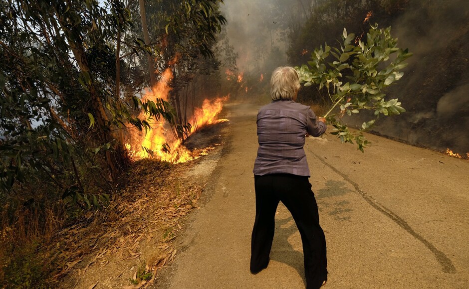 A woman uses a tree branch to fight a fire on the road leading to the village of Parada, near Mortagua. The Madeira fire forced the evacuation of more than 1,000 residents and tourists in the islands. Residents described chaotic nighttime scenes, with people fleeing the flames by car at high speed on the wrong side of the road. AP A woman uses a tree branch to fight a fire on the road leading to the village of Parada, near Mortagua. The Madeira fire forced the evacuation of more than 1,000 residents and tourists in the islands. Residents described chaotic nighttime scenes, with people fleeing the flames by car at high speed on the wrong side of the road. AP