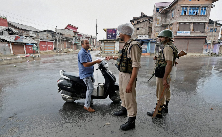 A security jawan checks the identification details of a Kashmiri as restrictions have been imposed on movements of common people in the Valley . PTI A security jawan checks the identification details of a Kashmiri as restrictions have been imposed on movements of common people in the Valley . PTI