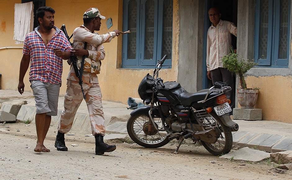 A youth is detained by an Indian paramilitary soldier a day after angry mobs burnt and vandalized buses from Tamil Nadu, in Bengaluru. One person was killed and another injured in police firing amid escalating tensions between the two states. (Photo: AP) A youth is detained by an Indian paramilitary soldier a day after angry mobs burnt and vandalized buses from Tamil Nadu, in Bengaluru. One person was killed and another injured in police firing amid escalating tensions between the two states. (Photo: AP)