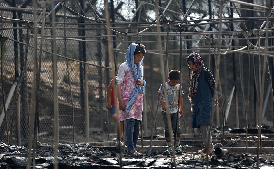 Migrants stand among the remains of a burned tent at the Moria migrant camp. At least nine people were arrested on accusations of damaging property and causing unrest and were expected to appear before a prosecutor, a police official in Athens said. Reuters Migrants stand among the remains of a burned tent at the Moria migrant camp. At least nine people were arrested on accusations of damaging property and causing unrest and were expected to appear before a prosecutor, a police official in Athens said. Reuters