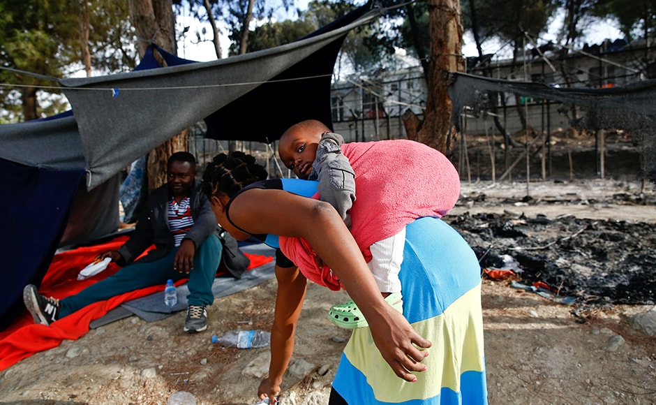 A migrant woman carries a baby as she stands next to the remains of a burned tent at the Moria migrant camp. Tensions have boiled over at overcrowded camps on Greece's islands as the slow processing of asylum requests adds to frustration over living conditions. Reuters A migrant woman carries a baby as she stands next to the remains of a burned tent at the Moria migrant camp. Tensions have boiled over at overcrowded camps on Greece's islands as the slow processing of asylum requests adds to frustration over living conditions. Reuters