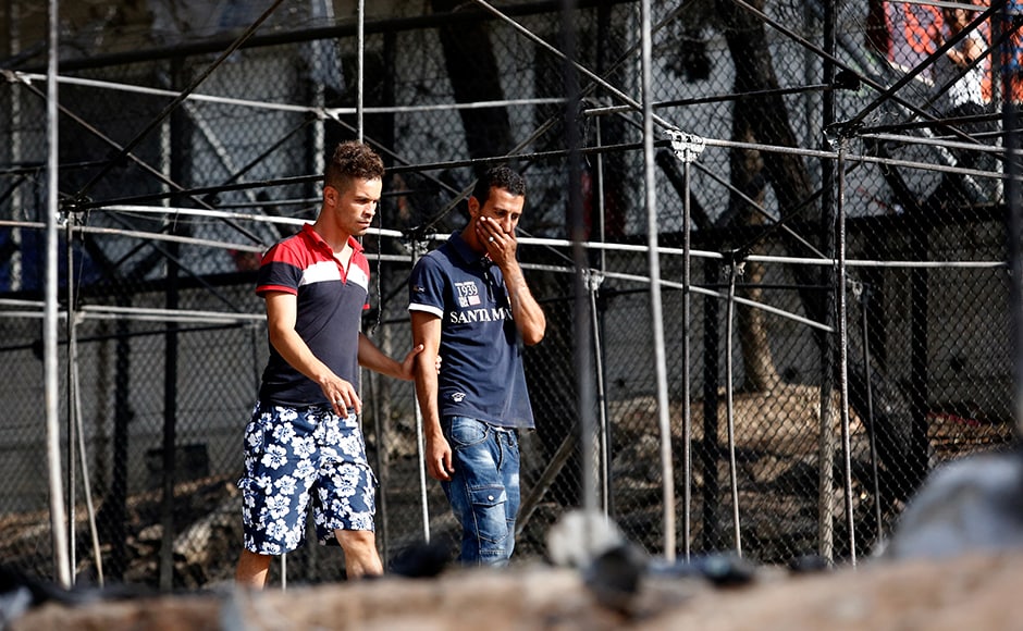 A migrant (R) reacts as he walks next to the remains of burned tents at the Moria migrant camp. Thousands have applied for asylum and the wait is long, ranging from weeks to months. Reuters A migrant (R) reacts as he walks next to the remains of burned tents at the Moria migrant camp. Thousands have applied for asylum and the wait is long, ranging from weeks to months. Reuters
