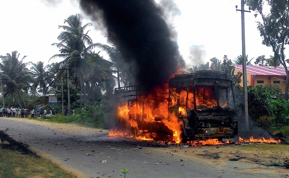 A vehicle torched by pro-Kannada activists in during a protest in Mandya district – epicentre of Mandya protest – on Monday. In view of the deteriorating situation, the Centre rushed 10 companies (about 1,000 personnel) of the special anti-riot paramilitary force RAF to Karnataka. (Photo: PTI) A vehicle torched by pro-Kannada activists in during a protest in Mandya district – epicentre of Mandya protest – on Monday. In view of the deteriorating situation, the Centre rushed 10 companies (about 1,000 personnel) of the special anti-riot paramilitary force RAF to Karnataka. (Photo: PTI)