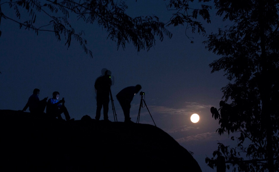 Tourists take photographs of the rising moon in Gauhati, India. AP Tourists take photographs of the rising moon in Gauhati, India. AP