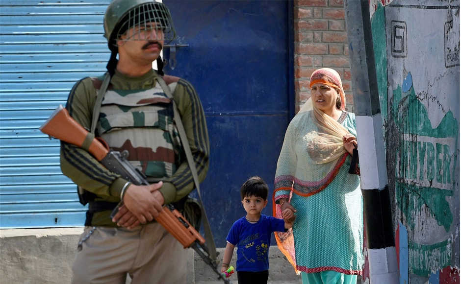 A woman and her son look on as a security guard stands at a road during curfew. Shops and business establishments remained closed and traffic was off the roads at Banihal and Bhaderwah in Ramban and Doda districts following a shutdown call that was given by a religious organisation. PTI A woman and her son look on as a security guard stands at a road during curfew. Shops and business establishments remained closed and traffic was off the roads at Banihal and Bhaderwah in Ramban and Doda districts following a shutdown call that was given by a religious organisation. PTI