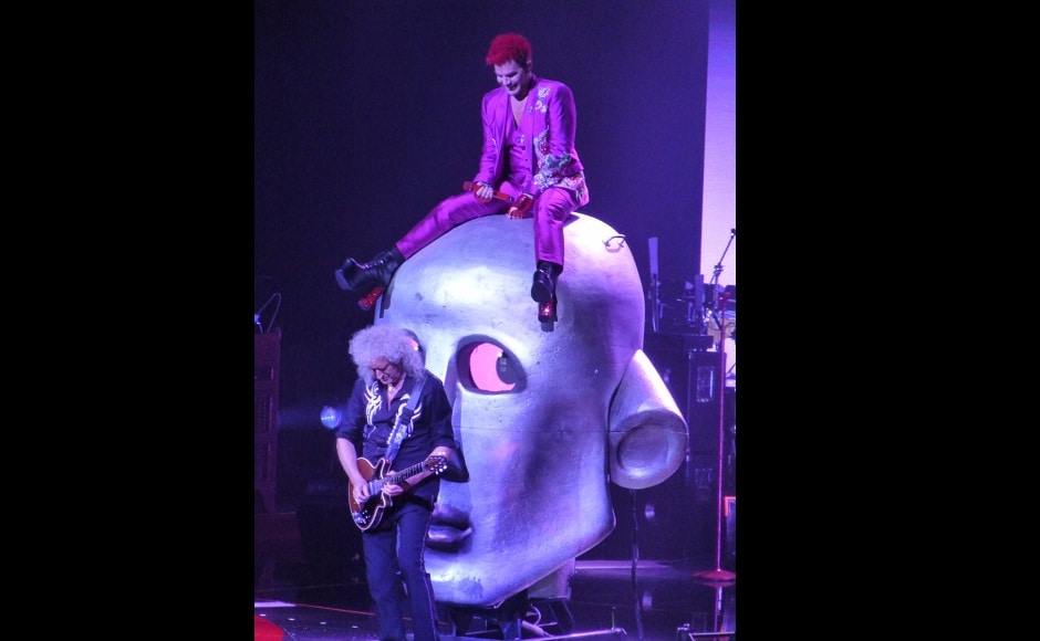 Adam Lambert sits atop a stage prop while Queen's Brian May plays the guitar. Image from Twitter Adam Lambert sits atop a stage prop while Queen's Brian May plays the guitar. Image from Twitter