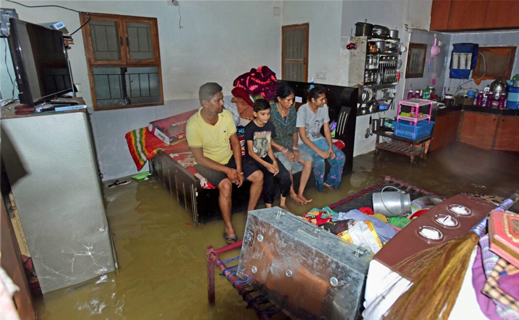 A family in a waterlogged house after heavy rainfall in Vejalpur in Ahmedabad on Thursday. Portions of at least 20 buildings collapsed due to heavy rains and waterlogging, officials said. PTI A family in a waterlogged house after heavy rainfall in Vejalpur in Ahmedabad on Thursday. Portions of at least 20 buildings collapsed due to heavy rains and waterlogging, officials said. PTI