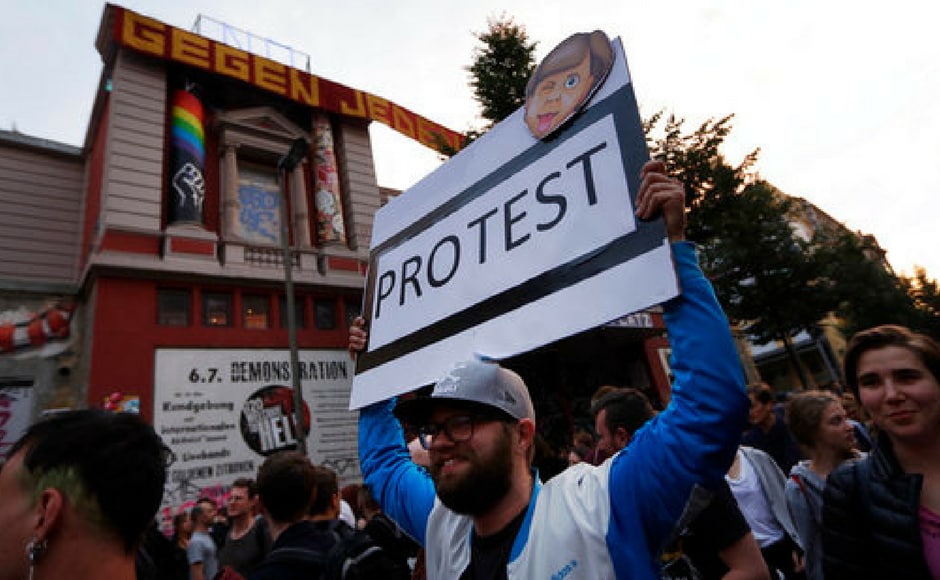 A demonstrator holds a poster with a altered image of German chancellor Angela Merkel during a dancing protest against the G20 summit in Hamburg. AP A demonstrator holds a poster with a altered image of German chancellor Angela Merkel during a dancing protest against the G20 summit in Hamburg. AP