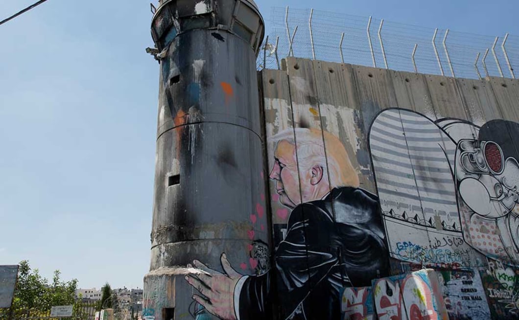 In one scene, Trump is shown hugging and kissing a real Israeli army watchtower built into the wall, as his left arm reaches around the tower. Little pink hearts flutter from Trump's mouth. AP In one scene, Trump is shown hugging and kissing a real Israeli army watchtower built into the wall, as his left arm reaches around the tower. Little pink hearts flutter from Trump's mouth. AP