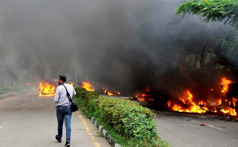 A cameraperson walks towards vehicles burning following violence caused by Dera Sacha Sauda followers after Gurmeet Ram Rahim's conviction in Panchkula. Nearly 32 people lost their lives in the clashes, as per latest reports. PTI A cameraperson walks towards vehicles burning following violence caused by Dera Sacha Sauda followers after Gurmeet Ram Rahim's conviction in Panchkula. Nearly 32 people lost their lives in the clashes, as per latest reports. PTI