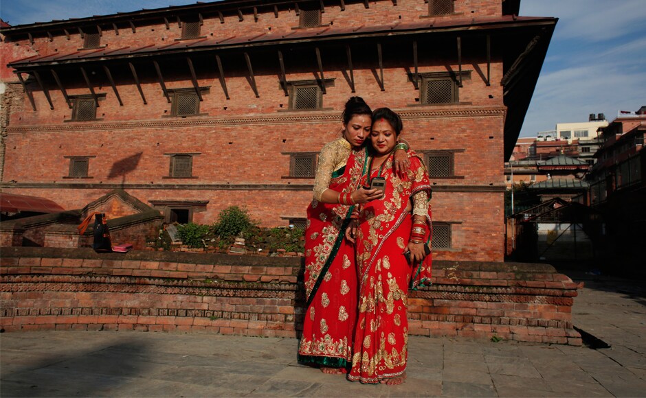 Two women check their phone after taking a selfie at the Pashupatinath temple. On the second day of the festival on Thursday, women spend the entire day without eating anything or drinking water. AP Two women check their phone after taking a selfie at the Pashupatinath temple. On the second day of the festival on Thursday, women spend the entire day without eating anything or drinking water. AP