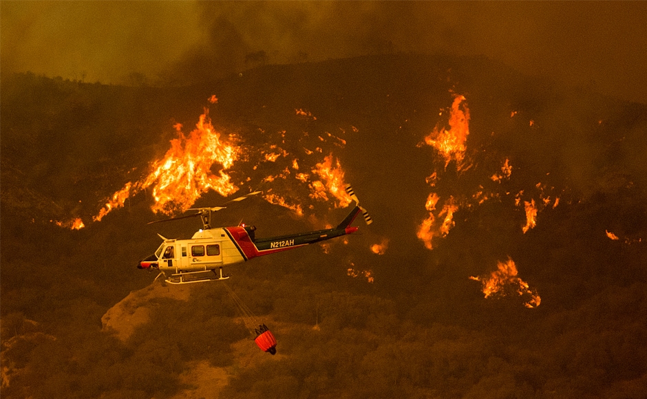 A helicopter carries water while trying to keep a wildfire from jumping a road. Despite the intensity of the fires that raged on multiple different fronts, authorities have reported only one fatality. AP A helicopter carries water while trying to keep a wildfire from jumping a road. Despite the intensity of the fires that raged on multiple different fronts, authorities have reported only one fatality. AP