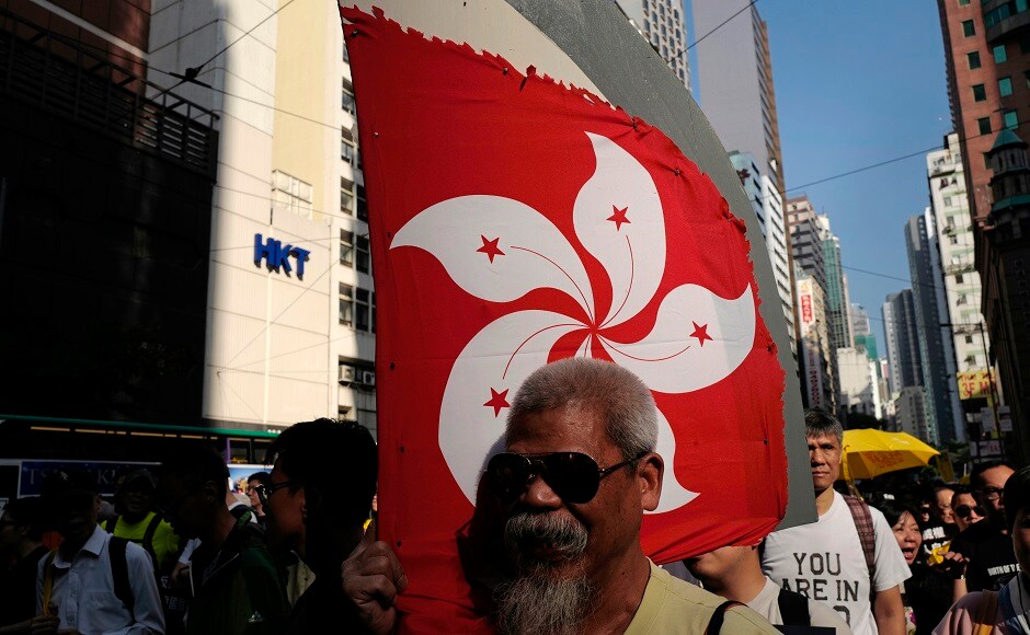 Some protesters played a recording of China's national anthem and paraded a doll bearing the sign: "When you hear the national anthem, don't eat. Stand up immediately." Others held up caricatures of leaders. AP Joshua Wong leads 'anti-authoritarian' protest in Hong Kong amidst growing Chinese pressure