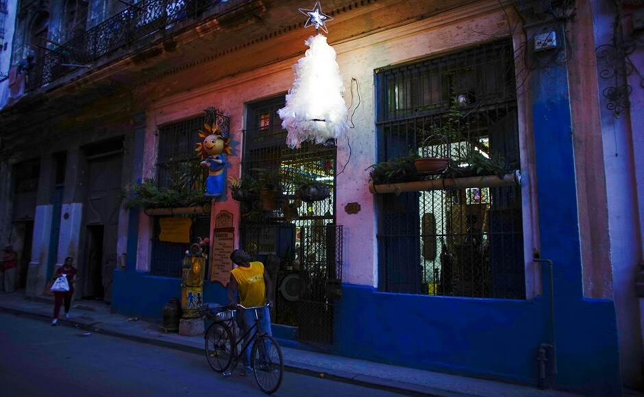 Artist Generoso Betancourt looks at his Christmas tree hanging over the door of his studio in downtown Havana, Cuba. REUTERS Christmas around the world: Lights, Santa hats and good cheer mark festivities