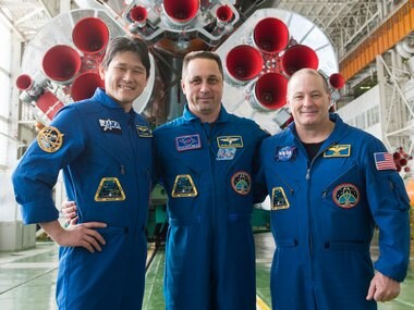 In the Integration Facility at the Baikonur Cosmodrome in Kazakhstan, crewmembers pose for pictures in front of the first stage of the Soyuz booster rocket. Image: Gagarin Cosmonaut Training Center/ NASA