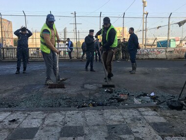 Baghdad municipality workers clean the scene of a double suicide bombing in Baghdad, Iraq, Monday. AP