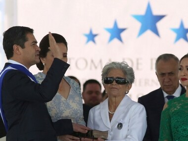 Honduran President Juan Orlando Hernandez takes the oath of office with his hand placed on a Bible held by his mother Elvira Alvarado, accompanied by his wife Ana Garcia, second left, and their daughter Ivonne Hernandez, right, at the National Stadium in Tegucigalpa, Honduras, Saturday, Jan. 27, 2018. AP