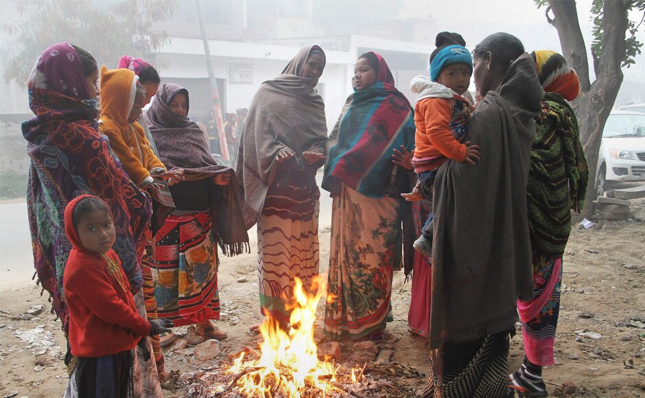 Women warm themselves near a fire during cold and fog morning in Jammu in Jammu and Kashmir on Wednesday. PTI Heavy fog disrupts normal life in Uttar Pradesh, Punjab, Haryana: Cold wave intensifies in several parts of India