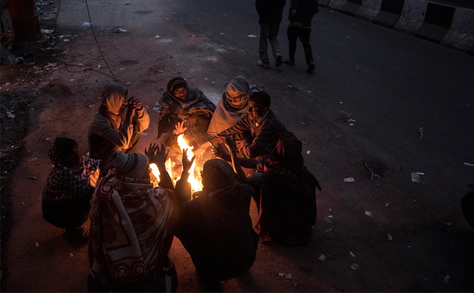 People sit around a fire to warm themselves during cold winter morning in New Delhi. On Thursday, low visibility due to thick fog led to train and flight services being cancelled in the national capital. PTI Heavy fog disrupts normal life in Uttar Pradesh, Punjab, Haryana: Cold wave intensifies in several parts of India