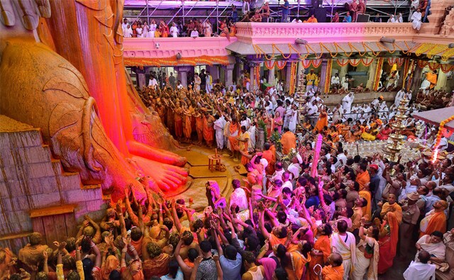 Devotees standing at the feet of the colossal rock-cut statue with devotion and spirit of the occasion were seen soaked in the colours of sandalwood and turmeric that was poured on the towering statue, as fragrance filled the air. PTI Devotees standing at the feet of the colossal rock-cut statue with devotion and spirit of the occasion were seen soaked in the colours of sandalwood and turmeric that was poured on the towering statue, as fragrance filled the air. PTI