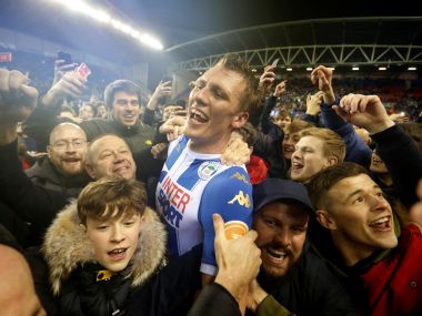 Wigan Athletics Dan Burn celebrates with fans on the pitch after the win over Manchester City. Reuters