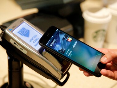 A man uses an iPhone 7 smartphone to demonstrate Apple Pay at a cafe. Image: Reuters