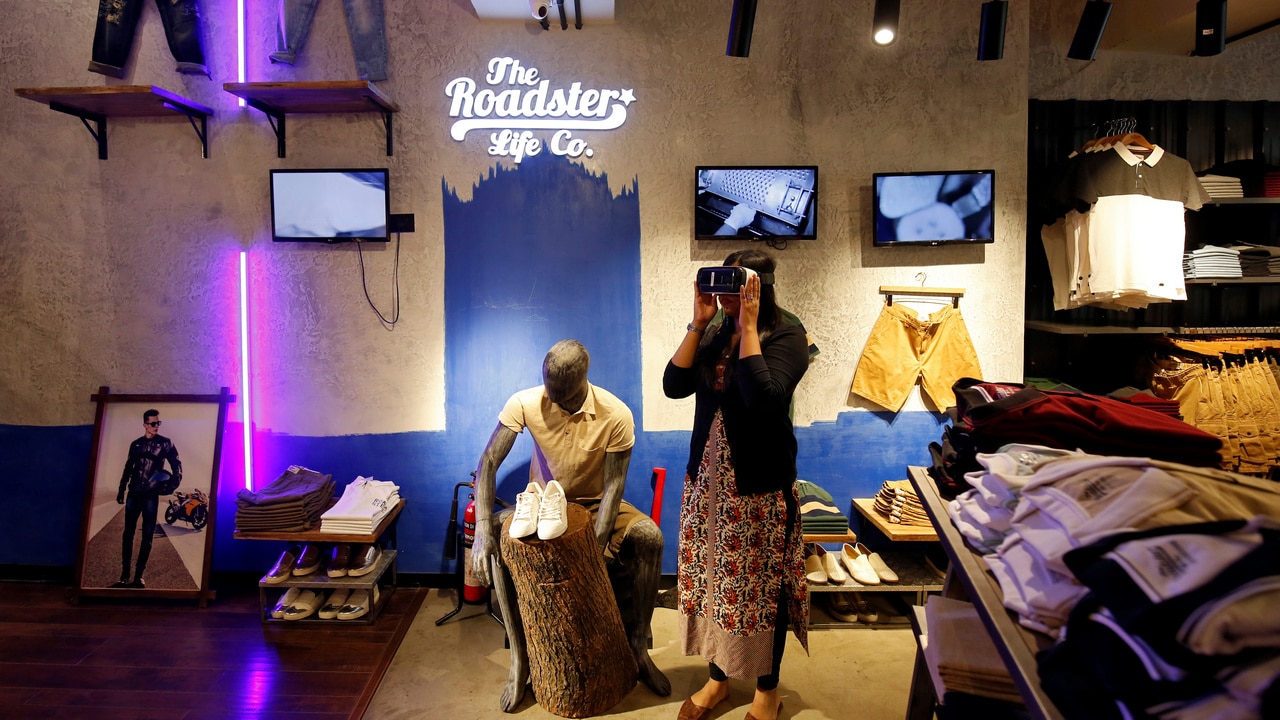 A customer poses with a virtual reality headset as she browses through a catalog of products inside a Roadster store. Image: Reuters