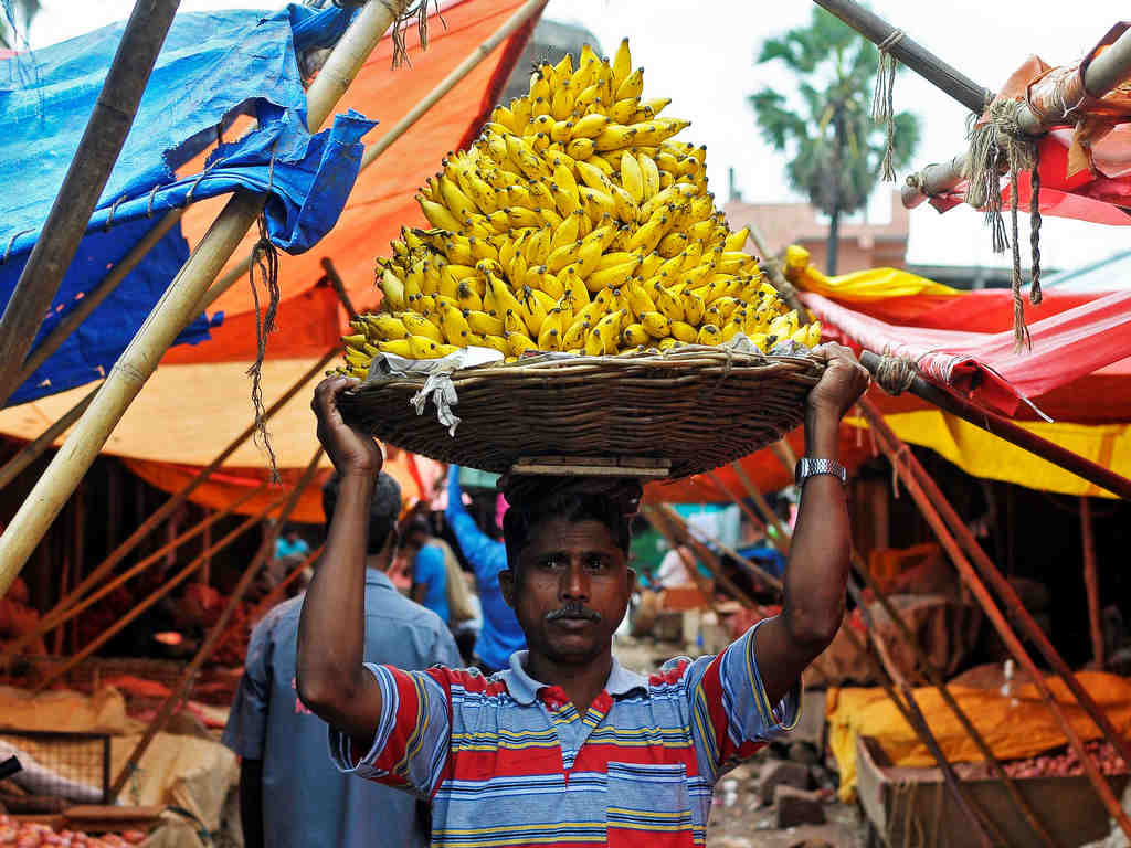A labourer carries a basket of bananas inside a wholesale fruit and vegetable market in Bengaluru, India, August 22, 2016. REUTERS/ Abhishek N. Chinnappa - S1BETWWQYUAA