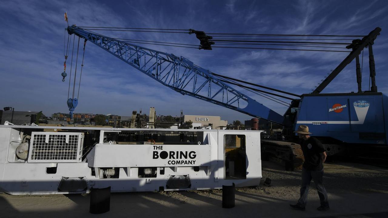 Electric locomotives and tunnel boring equipment are displayed before an unveiling event. Image: AP