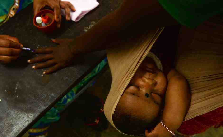 A woman gets her finger inked as her child sleeps at a polling station in Chennai. AFP A woman gets her finger inked as her child sleeps at a polling station in Chennai. AFP