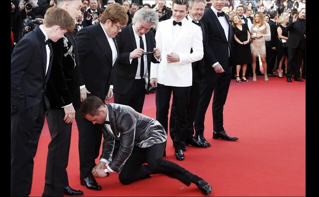 Taron Egerton ties Sir Elton John's shoe on the red carpet at the Rocketman premiere at Cannes 2019 | Twitter Taron Egerton ties Sir Elton John's shoe on the red carpet at the Rocketman premiere at Cannes 2019 | Twitter