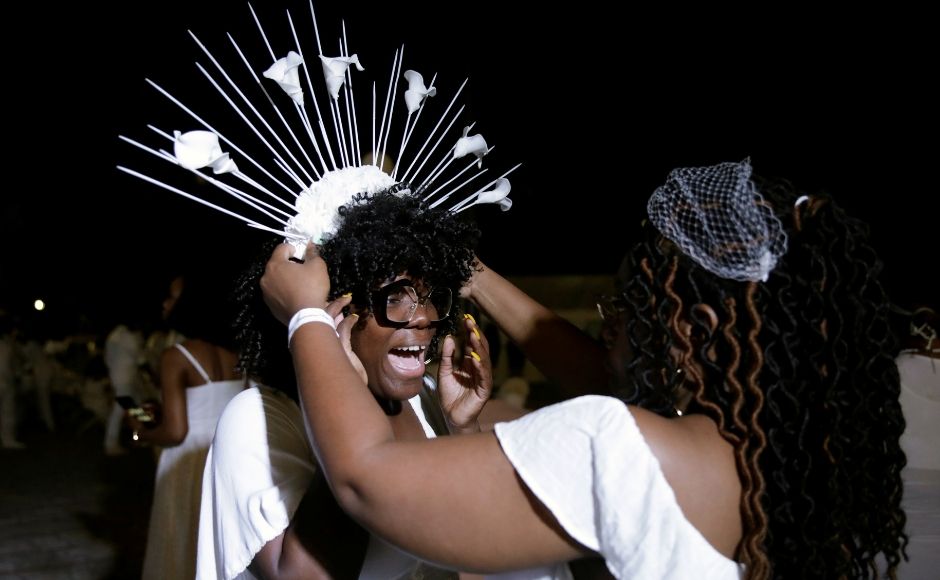 Dressed all in white, one attendee sets a headband on another woman during the 2019 Haiti Dîner en Blanc event in Cap Haitien. Reuters/ Andres Martinez Casares Dressed all in white, one attendee sets a headband on another woman during the 2019 Haiti Dîner en Blanc event in Cap Haitien. Reuters/ Andres Martinez Casares