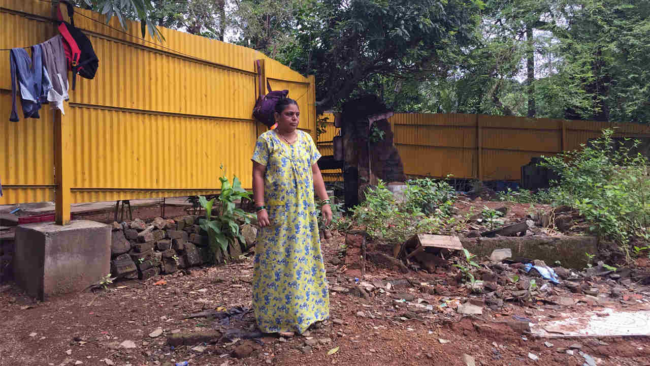 sha Bhoye, a member of a tribal community residing inside Aarey, stands in front of the barricade raised by the authorities in front of her house. image credit: Kartik Chandramouli/Mongabay.