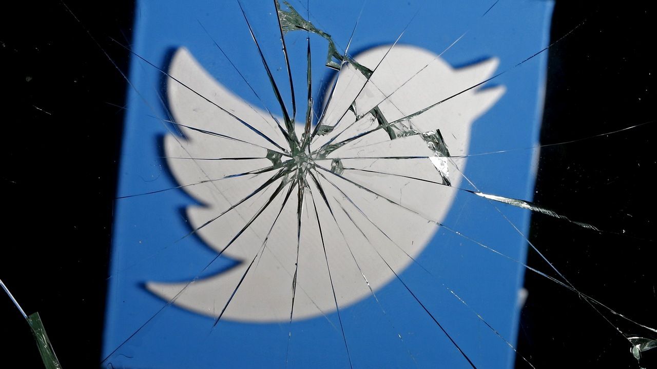 A 3D-printed Twitter logo is seen through broken glass, in this picture illustration taken