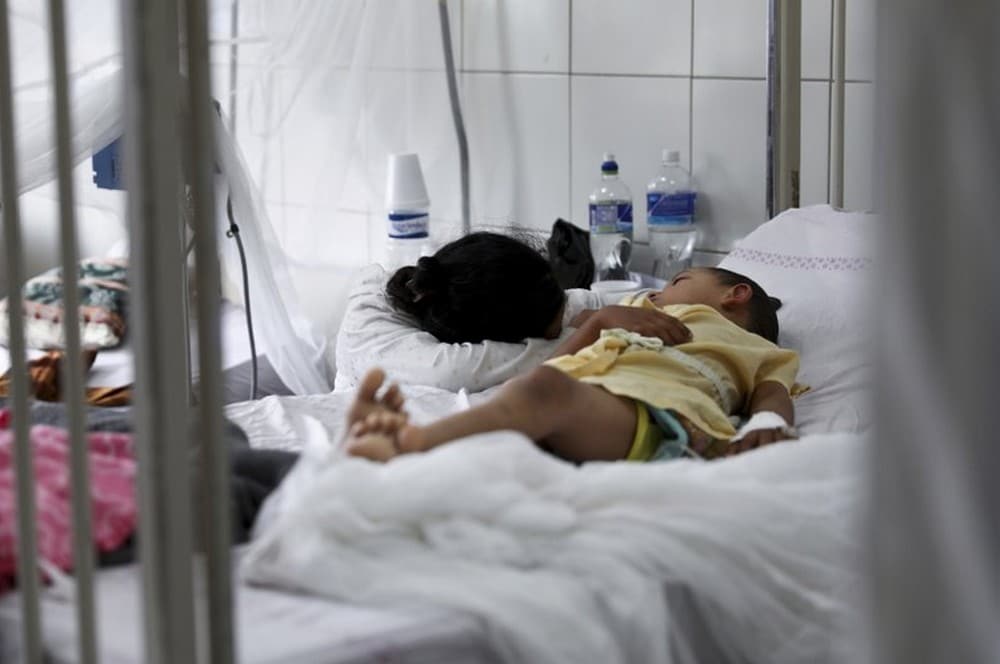 A relative embraces a young patient receiving treatment for dengue at the University School Hospital in Tegucigalpa, Honduras. Image credit: AP