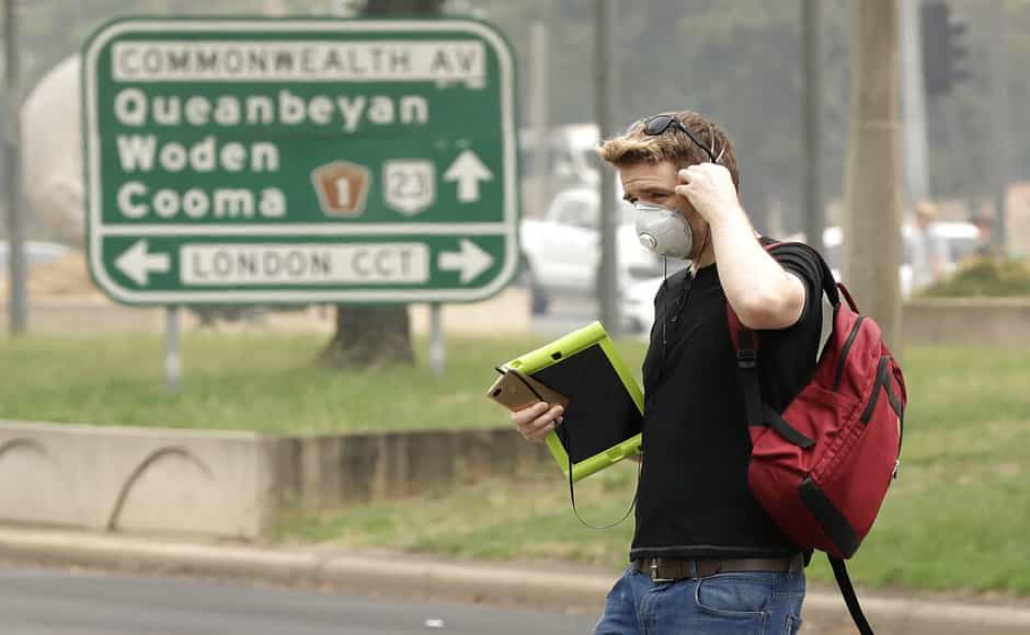 A pedestrian wears a mask as smoke shrouds the Australian capital of Canberra, Australia. More than 50,000 people were without power and some towns had no access to drinking water after catastrophic fires ripped through the region on 31 December sending the sky blood red and destroying towns. AP A pedestrian wears a mask as smoke shrouds the Australian capital of Canberra, Australia. More than 50,000 people were without power and some towns had no access to drinking water after catastrophic fires ripped through the region on 31 December sending the sky blood red and destroying towns. AP