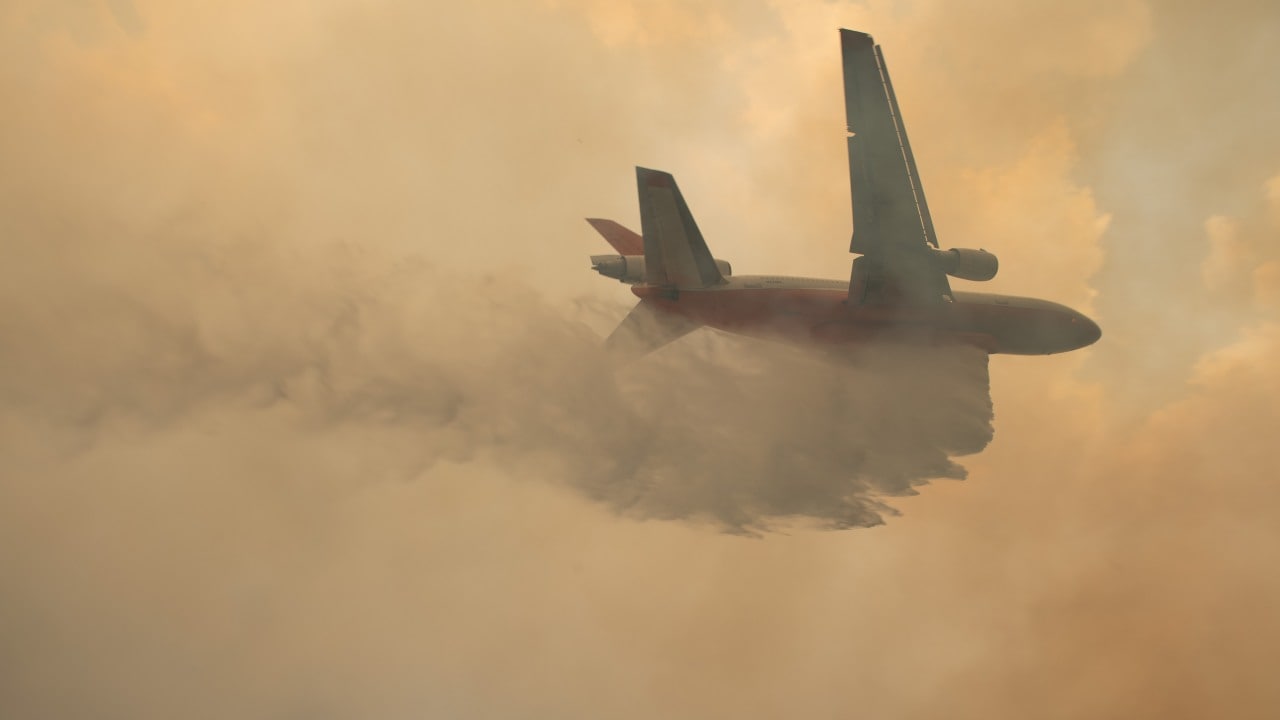 A plane drops water over wildfires burning in the vicinity of Tapitallee, New South Wales, Australia on 4 January 2020. High winds and temperatures over 100 degrees Fahrenheit were likely to exacerbate fires already raging out of control on Saturday; Officials in New South Wales said they expected to lose more houses over the weekend. Image: Matthew Abbott/NYT