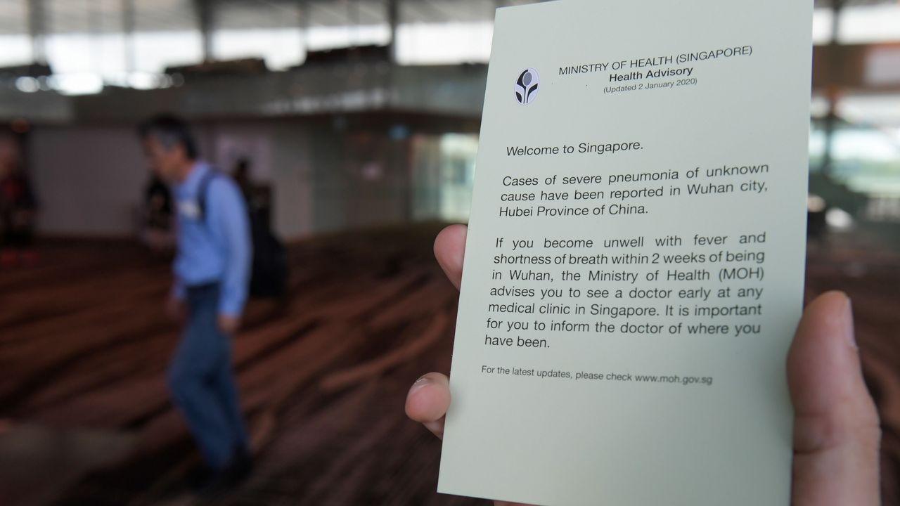 An airport staff holds health advisory cards for passengers at Changi International airport in Singapore on January 22, 2020 as authorities increased measure against coronavirus. - A new virus that has killed nine people, infected hundreds and already reached the United States could mutate and spread, China warned January 22, as authorities scrambled to contain the disease during the Lunar New Year travel season. (Photo by ROSLAN RAHMAN / AFP) (Photo by ROSLAN RAHMAN/AFP via Getty Images)