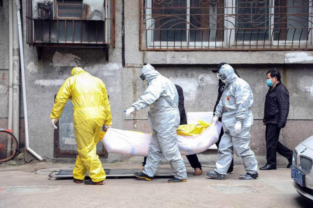 Funeral home workers remove the body of a person suspect to have died from a virus outbreak from a residential building in Wuhan in central China's Hubei Province. Image credit: AP