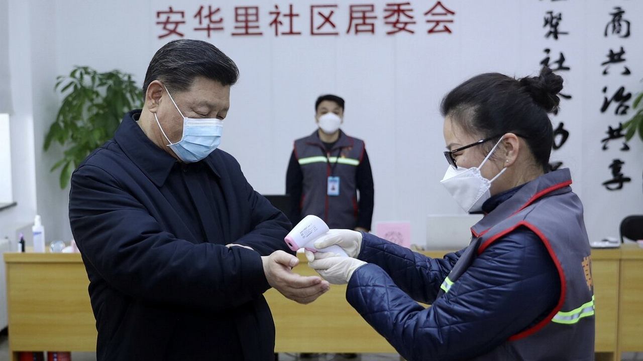 Chinese President Xi Jinping, left, wearing a protective face mask, receives a temperature check as he visits a community health center in Beijing. Image credit: AP