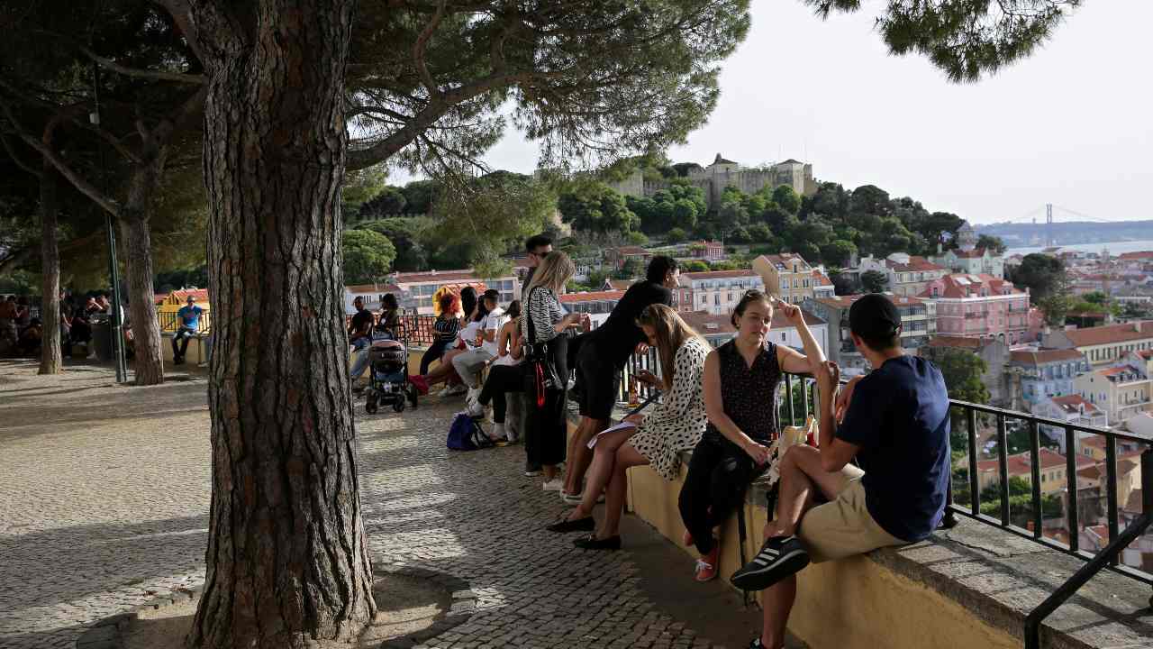 People enjoy the weather from a viewpoint overlooking Lisbon's old center, Sunday, May 3, 2020. After six weeks of a government declared state of emergency, Portugal is starting to loosen its coronavirus restrictions, with small stores, hair salons, libraries, car showrooms and government tax departments allowed to reopen from next Monday. (AP Photo/Armando Franca)