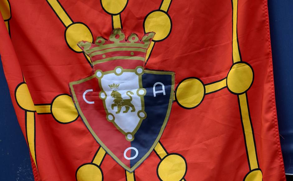 Formed in 1920, the club's badge reflects their kit colours; a red shirt paired with navy shorts. The word Osasuna means ‘health’ in Basque and can be used to mean ‘strength’ which explains the lion’s presence amid the shield. The crown that sits atop the crest represents the escudo of the ancient Kingdom of Navarre from where they are based. Furthermore, the chain draped around the lion comes from the Navarre shield. Formed in 1920, the club's badge reflects their kit colours; a red shirt paired with navy shorts. The word Osasuna means ‘health’ in Basque and can be used to mean ‘strength’ which explains the lion’s presence amid the shield. The crown that sits atop the crest represents the escudo of the ancient Kingdom of Navarre from where they are based. Furthermore, the chain draped around the lion comes from the Navarre shield.