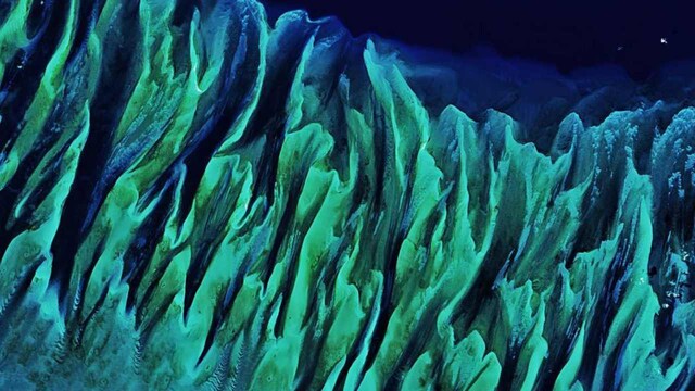This is an underwater masterpiece photographed from above is the Great Bahama Bank and was dry land during past ice ages, but it slowly submerged as sea levels rose. Today, the bank is covered by water, though it can be as shallow as two meters deep in places. The bank itself is a combination of white carbonate sand and limestone, mainly from the skeletal fragments of corals. The wave-shaped ripples in the image are sand on the seafloor. The curves follow the slopes of the dunes, which were likely shaped by a fairly strong current near the sea bottom. Sand and seagrass are present in different quantities and depths, giving the image it’s a striking range of blues and greens. Image Credits: NASA Earth Observatory images by Joshua Stevens This is an underwater masterpiece photographed from above is the Great Bahama Bank and was dry land during past ice ages, but it slowly submerged as sea levels rose. Today, the bank is covered by water, though it can be as shallow as two meters deep in places. The bank itself is a combination of white carbonate sand and limestone, mainly from the skeletal fragments of corals. The wave-shaped ripples in the image are sand on the seafloor. The curves follow the slopes of the dunes, which were likely shaped by a fairly strong current near the sea bottom. Sand and seagrass are present in different quantities and depths, giving the image it’s a striking range of blues and greens. Image Credits: NASA Earth Observatory images by Joshua Stevens